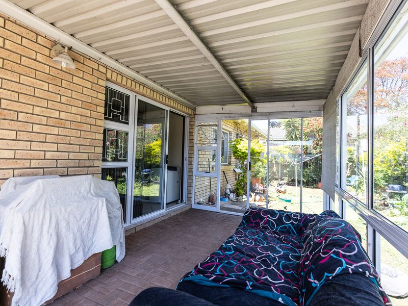 Enclosed patio area featuring brick walls, paved flooring, and sliding glass doors providing access to the rear garden.