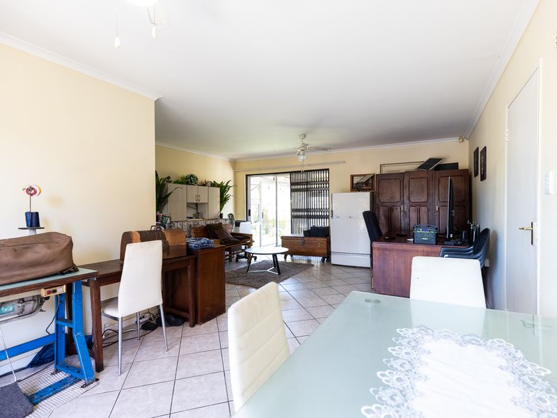 Spacious open-plan living area featuring tiled flooring, a ceiling fan, and large sliding glass doors providing access to the outdoor space.