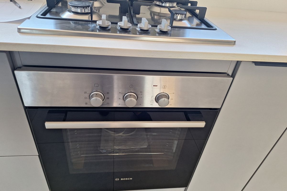 A modern kitchen featuring a built-in Bosch oven and gas hob set into a clean stone countertop with contemporary cabinetry.