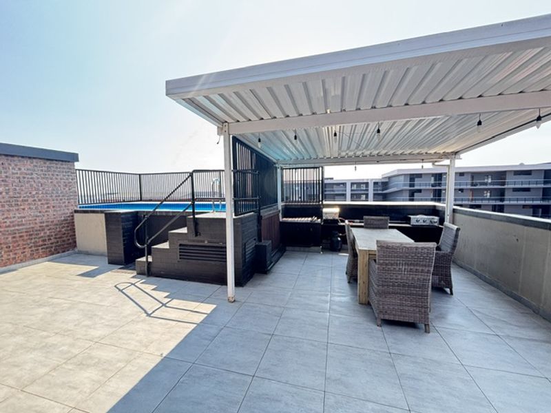 Spacious rooftop balcony featuring a private plunge pool, covered entertainment area with built-in braai, and modern tiled flooring.