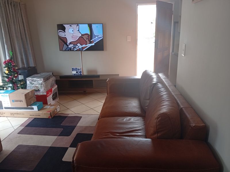 A living room area featuring tiled flooring and direct access to an external door, providing a functional space for relaxation.
