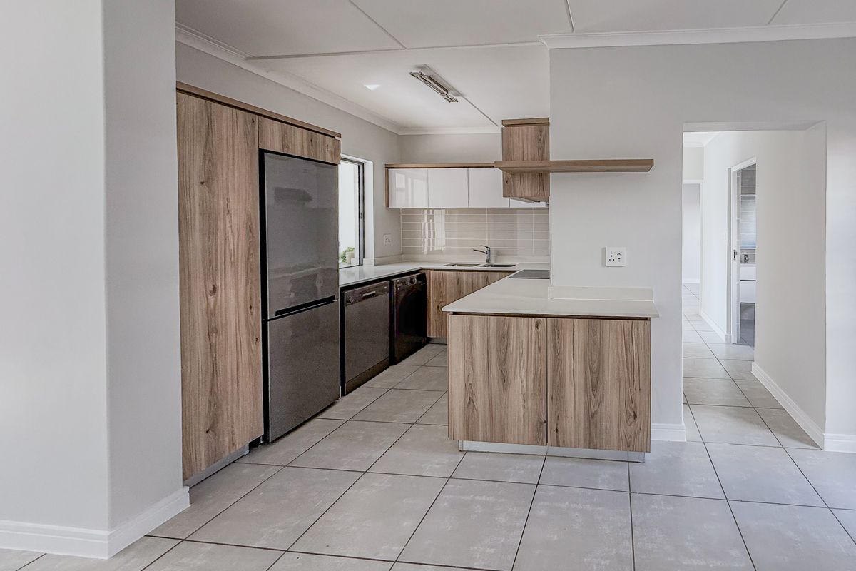Modern kitchen featuring wood-grain cabinetry, stone countertops, tiled flooring, and integrated appliances in a clean, neutral design.