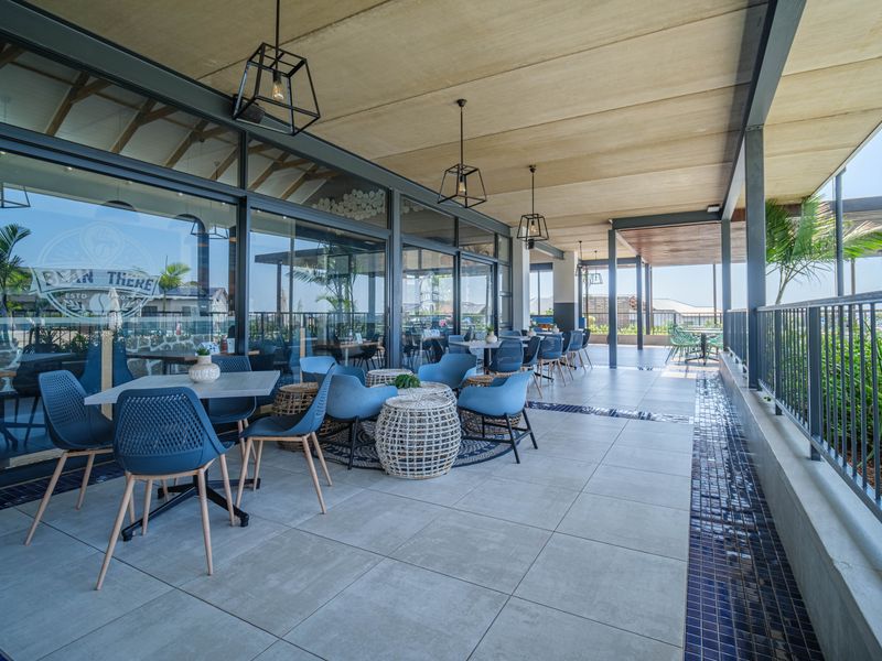 Spacious covered patio featuring large format floor tiles, modern metal balustrades, and extensive sliding glass doors, ideal for outdoor dining and relaxation.