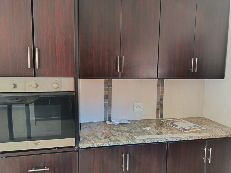 A functional kitchen area featuring dark wood-finish cabinetry, granite countertops, and a built-in oven, offering a clean and practical workspace.