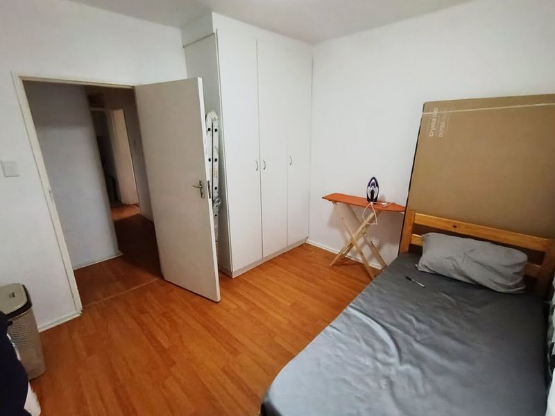 A functional bedroom featuring laminate flooring and a built-in wardrobe, offering a clean and simple space ready for personalization.