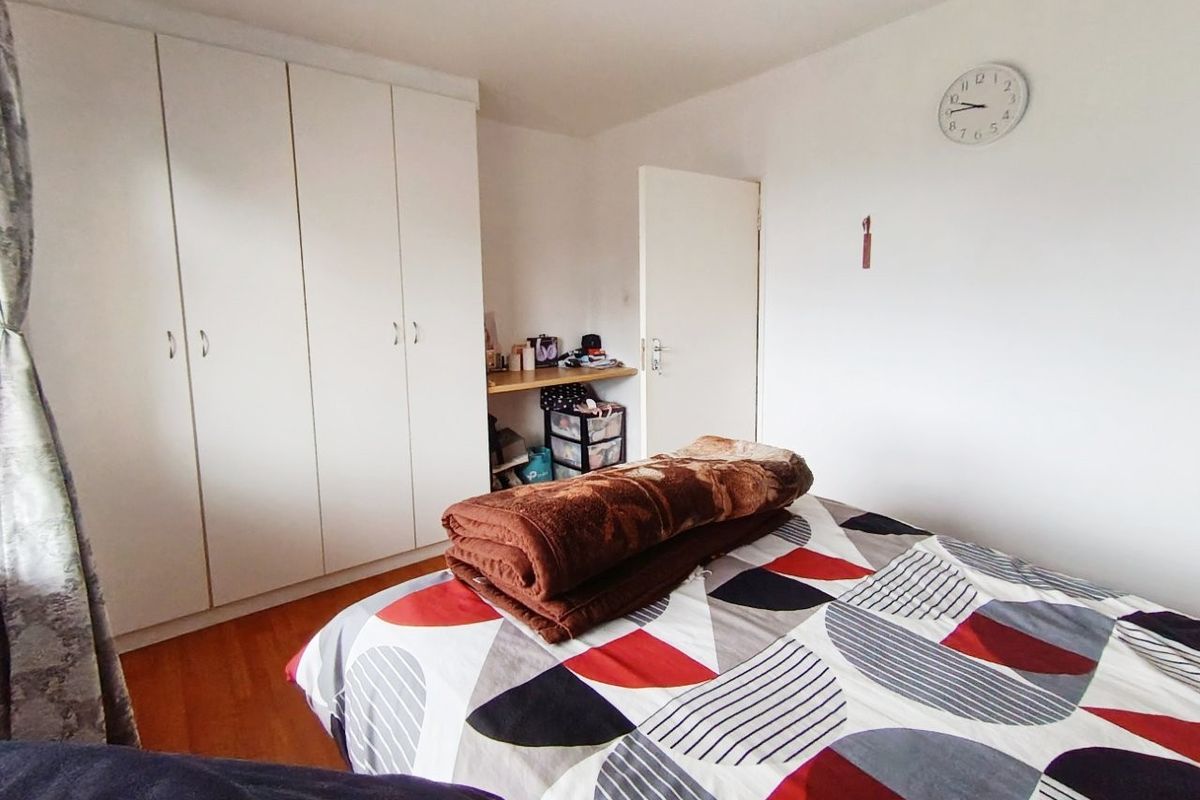 A bedroom featuring laminate flooring and white built-in cupboards with an integrated desk area.