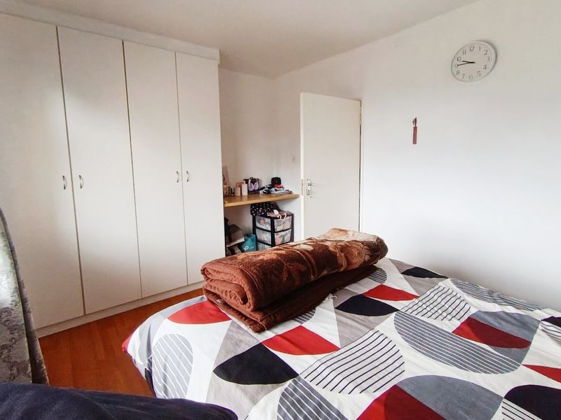 A bedroom featuring laminate flooring and white built-in cupboards with an integrated desk area.