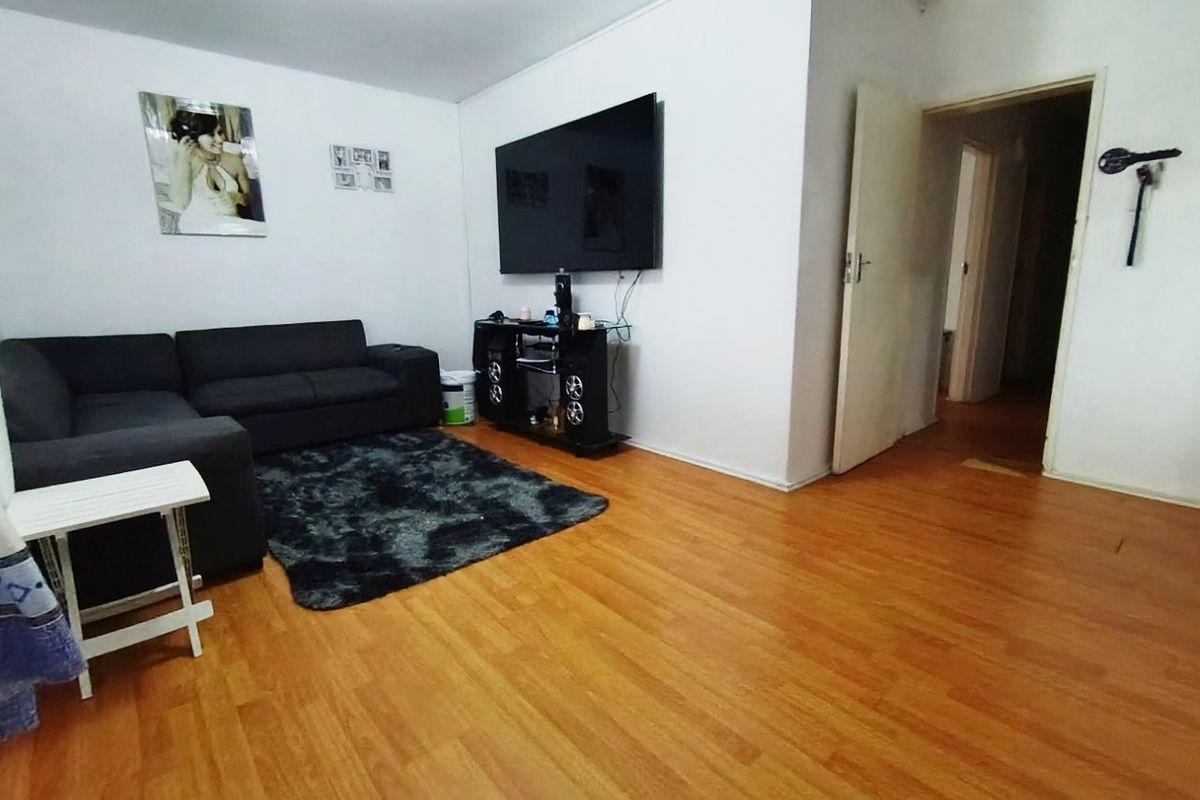A living room featuring laminate flooring and access to an adjoining hallway.