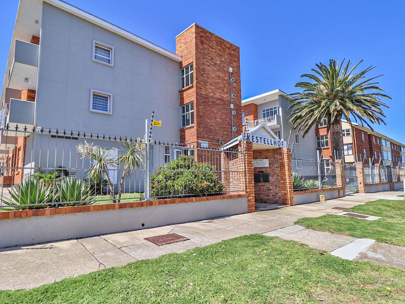 Front exterior view of Kestellhof apartment complex featuring brick and rendered facade, secure perimeter fencing, and established landscaping.