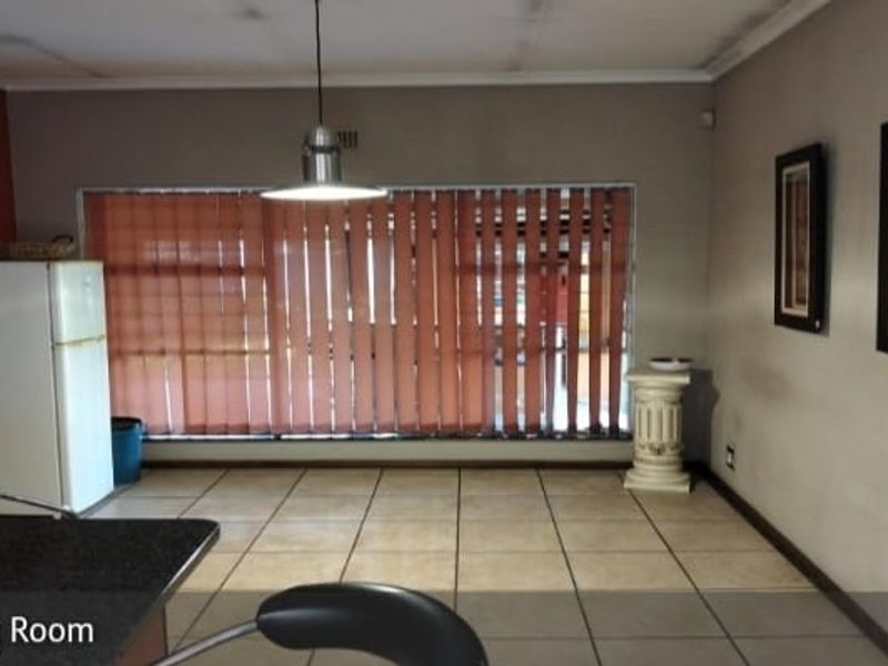 Dining area featuring tiled flooring, pendant lighting, and vertical blinds, with visible ceiling water staining requiring attention.
