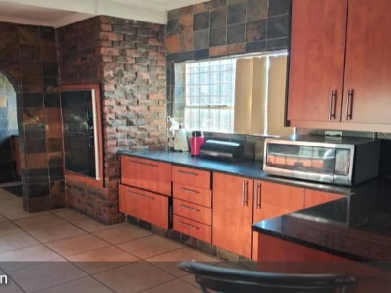 Kitchen featuring dark wood cabinetry, granite countertops, and a distinctive brick feature wall with tiled flooring and an arched entryway.
