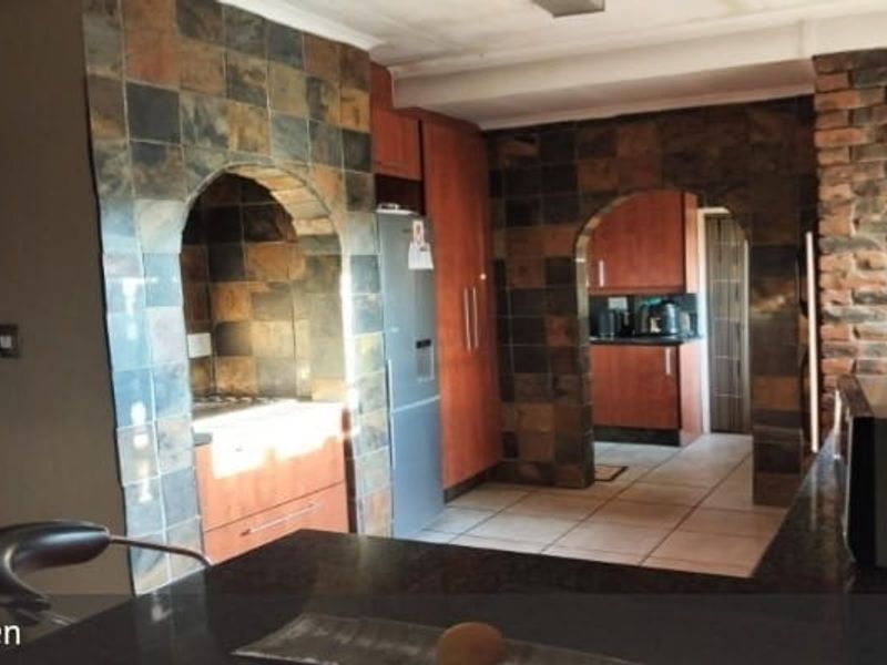 Kitchen featuring stone tile accents, arched architectural details, built-in cabinetry, and granite countertops with a functional layout.