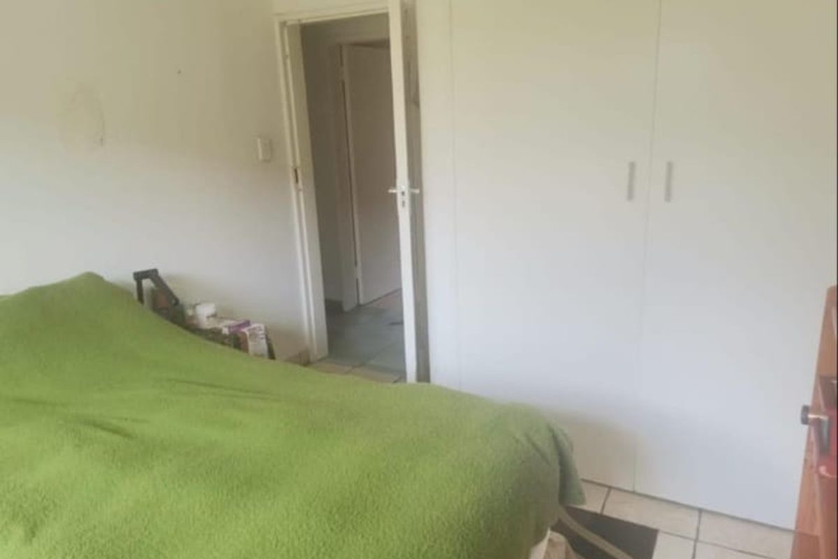 A bedroom featuring built-in cupboards and tiled flooring, requiring minor cosmetic attention to wall surfaces.