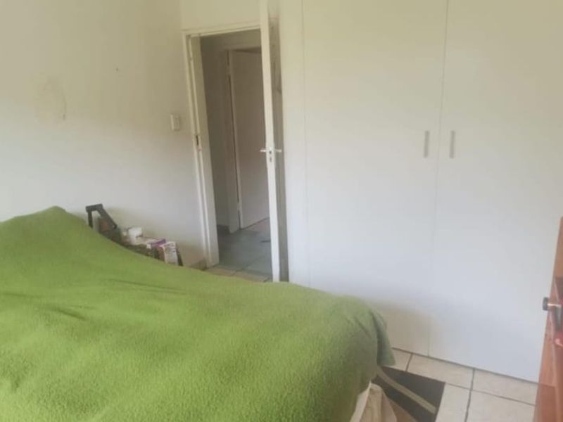 A bedroom featuring built-in cupboards and tiled flooring, requiring minor cosmetic attention to wall surfaces.