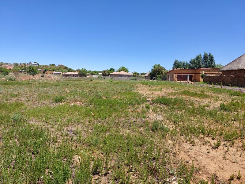 A vacant residential plot of land featuring natural vegetation and perimeter wire fencing, situated in a developed neighborhood.