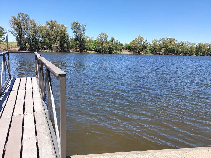 A scenic view of a river from a private wooden jetty with metal railings.