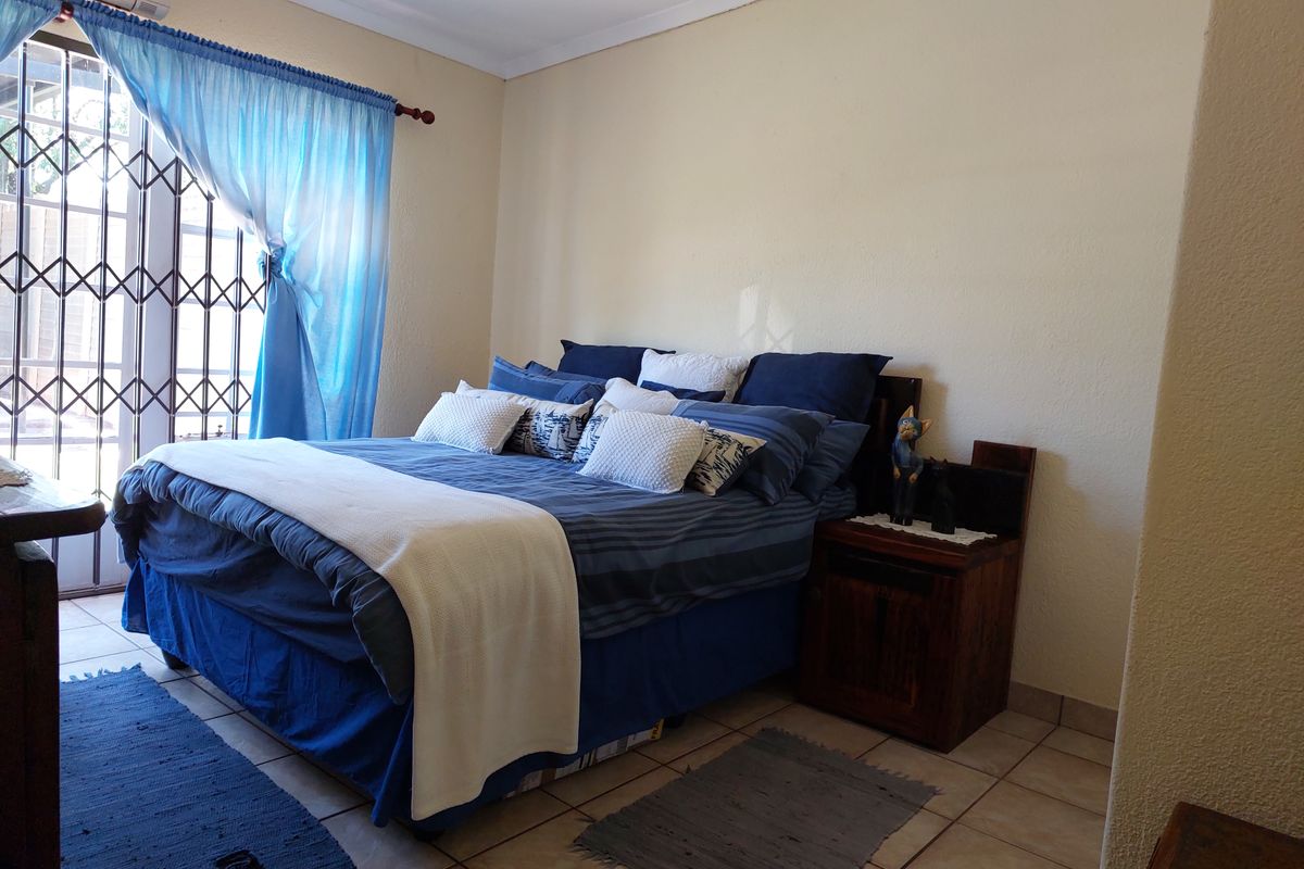 A bedroom featuring tiled flooring, an air conditioning unit, and a security gate leading to the exterior.