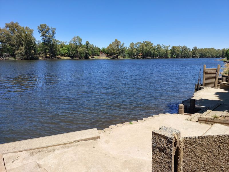 A scenic view of the river featuring a concrete jetty and direct water access, surrounded by mature trees.