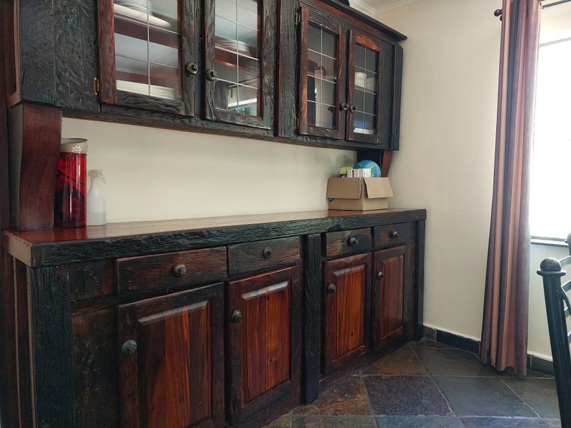 A dining area featuring rustic built-in wooden cabinetry with glass display doors and durable slate tile flooring.