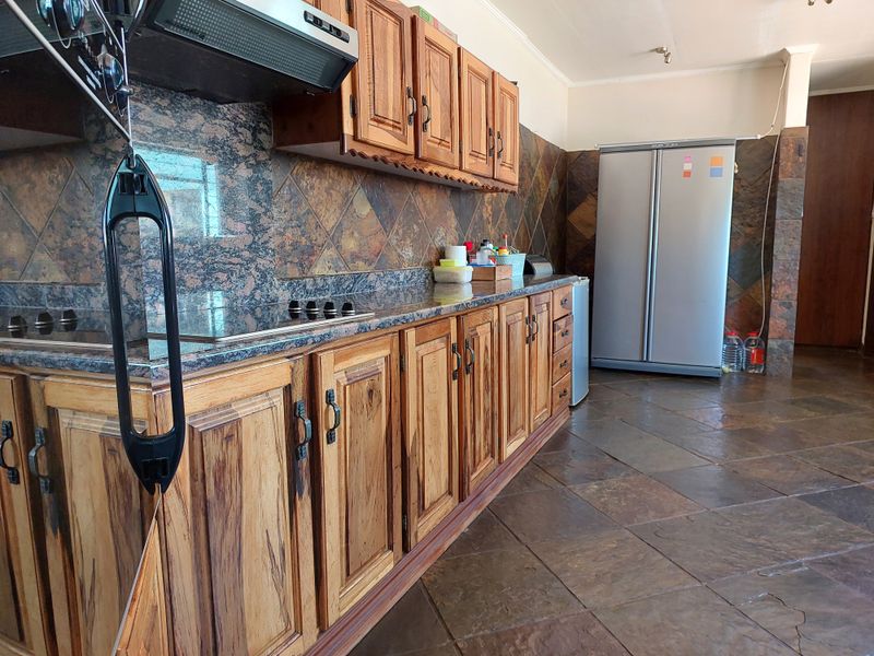 Kitchen featuring wooden cabinetry, granite countertops, and slate tile finishes. The space includes a built-in hob and extractor fan.