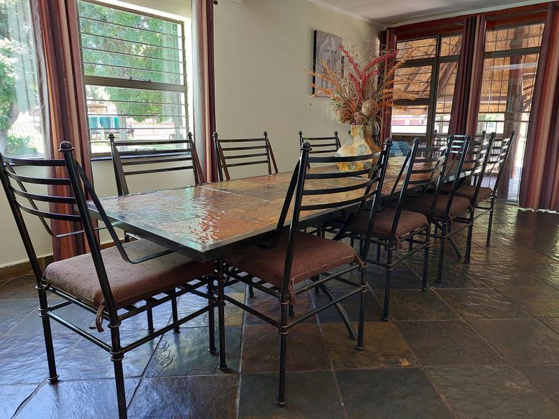 A dining area featuring natural slate tile flooring, large windows, and sliding glass doors providing access to the outdoor space.