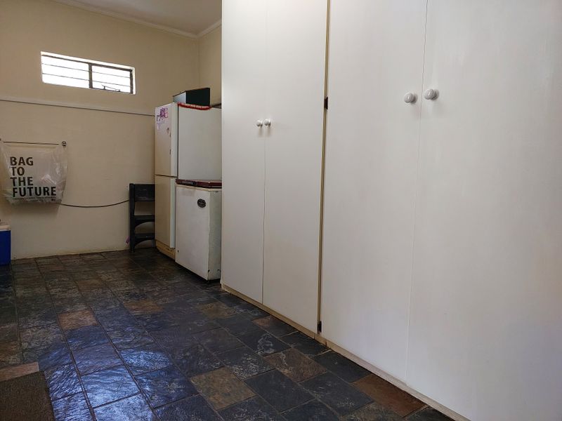 A functional laundry area featuring extensive built-in storage cupboards and durable slate tile flooring.