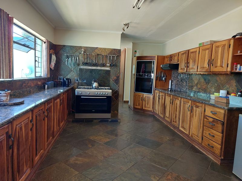 Spacious kitchen featuring solid wood cabinetry, granite countertops, slate tile flooring, and built-in appliances including a double oven and gas stove.
