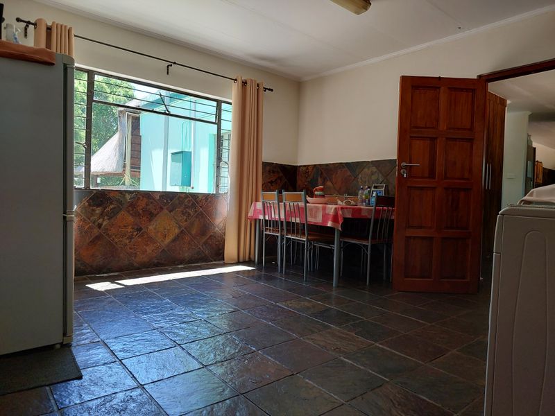 Dining area featuring slate tile flooring and matching wall cladding, with a timber door and steel-framed window providing natural light.
