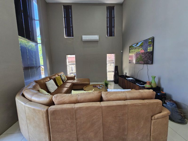 Spacious living room featuring high ceilings, large vertical windows for natural light, and a wall-mounted split-system air conditioner.