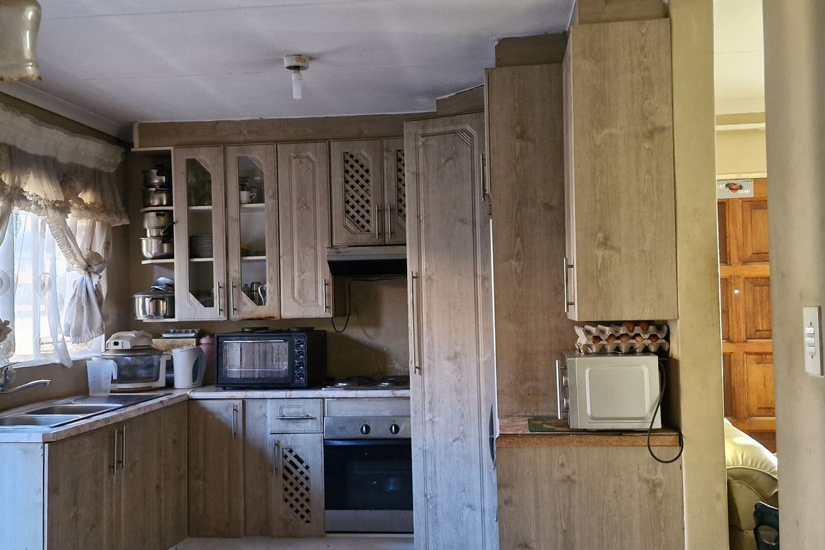 A functional kitchen featuring wood-look cabinetry, built-in oven, extractor fan, and laminate countertops, offering potential for modernization and cosmetic updates.