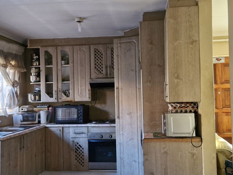 A functional kitchen featuring wood-look cabinetry, built-in oven, extractor fan, and laminate countertops, offering potential for modernization and cosmetic updates.