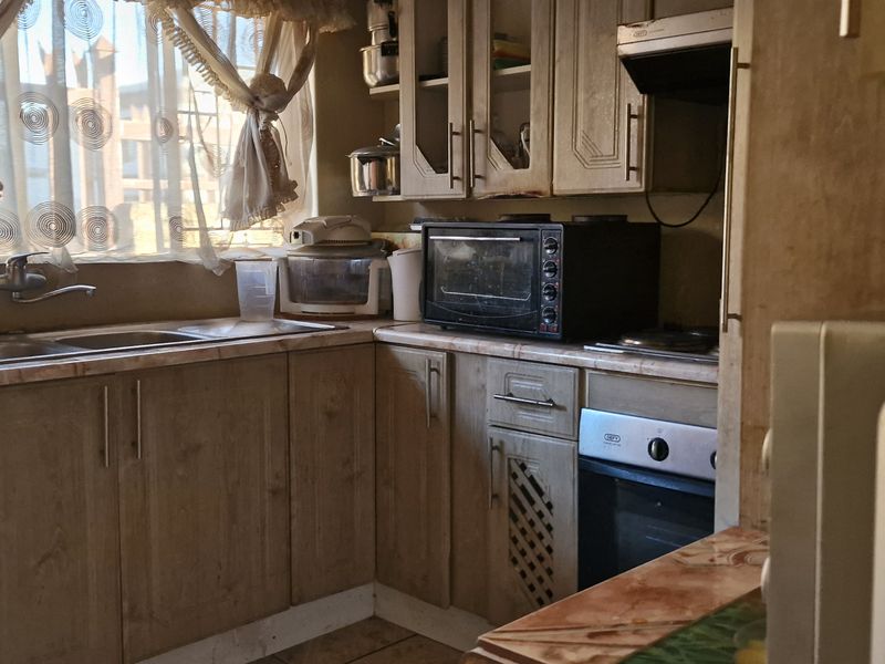 A functional kitchen featuring wood-look laminate cabinetry, a double bowl sink, and built-in oven with extractor fan.