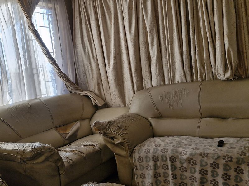 A living room area featuring large windows with security bars and full-length curtains.
