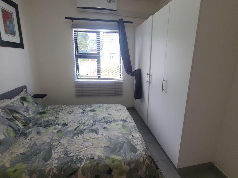 A well-maintained bedroom featuring tiled flooring, a large built-in wardrobe, and a split-system air conditioning unit.