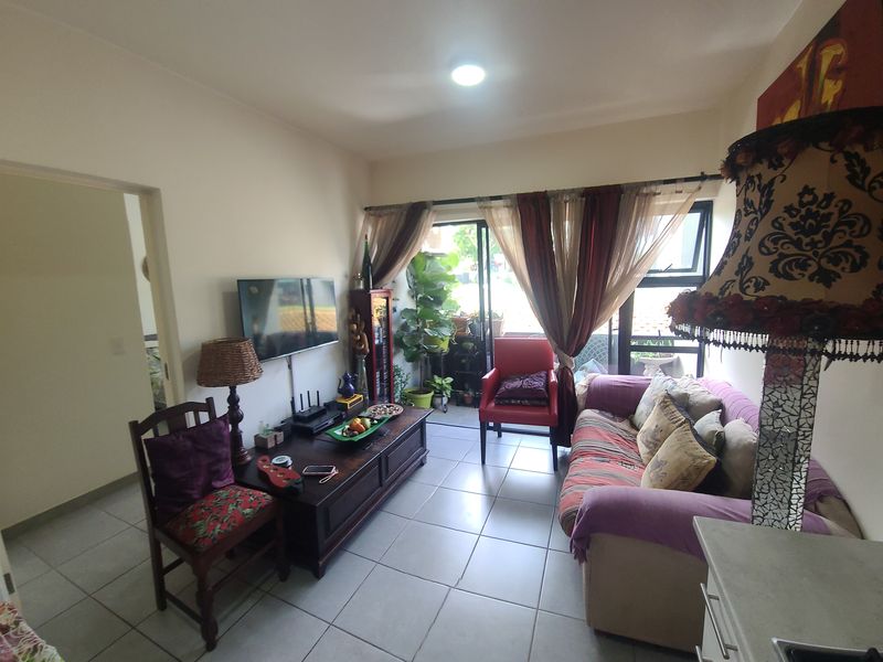 A living room featuring tiled flooring and a large sliding glass door that provides access to an outdoor balcony area.