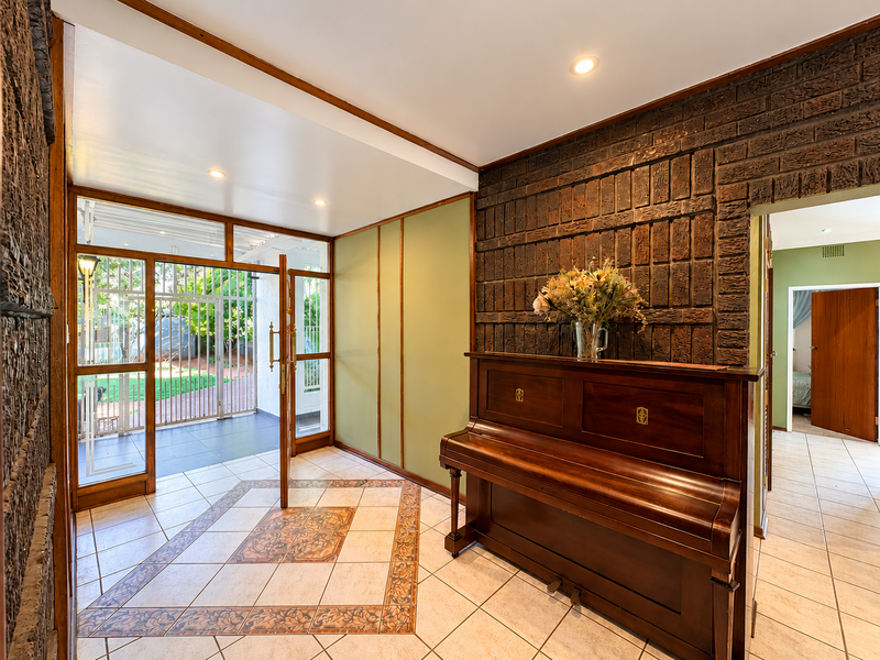 Welcoming entrance hall featuring a distinctive exposed brick wall, decorative tiled flooring, and direct access to the outdoor patio area.