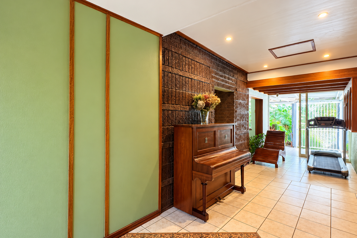 Spacious living area featuring a distinctive exposed brick wall, tiled flooring, and large sliding glass doors that provide access to the outdoor space.