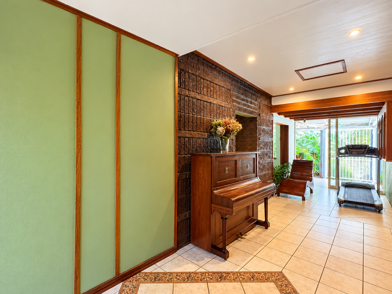 Spacious living area featuring a distinctive exposed brick wall, tiled flooring, and large sliding glass doors that provide access to the outdoor space.
