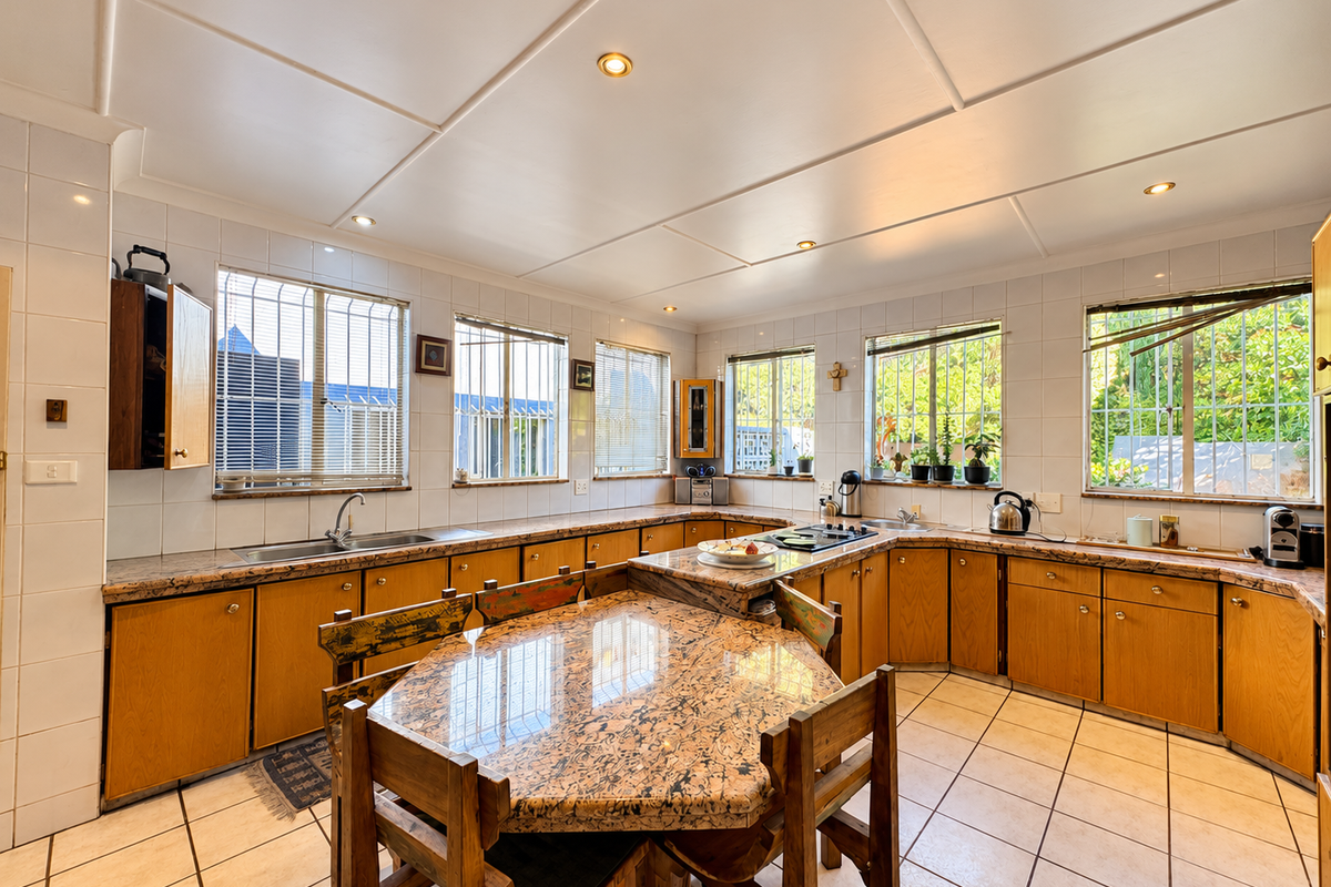 Spacious kitchen featuring extensive granite countertops, ample built-in cabinetry, tiled flooring, and multiple windows providing natural light.