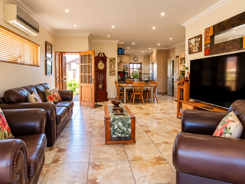 Spacious open-plan living and dining area featuring tiled flooring, recessed lighting, and seamless flow to the kitchen and outdoor access.