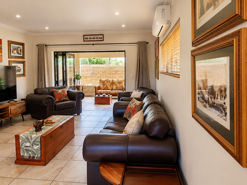 Spacious living room featuring tiled flooring, recessed downlights, and bi-fold doors opening to an outdoor patio area.