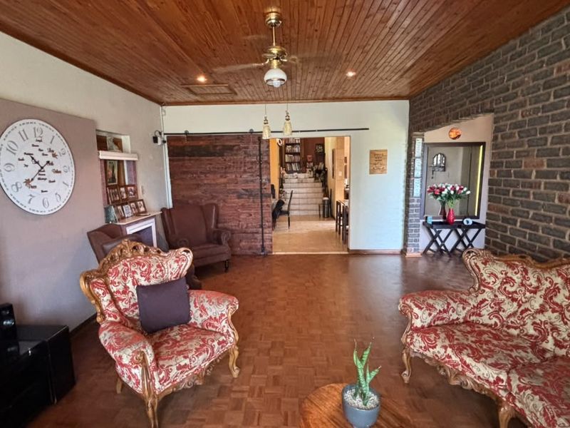 Spacious living room featuring a warm timber ceiling, exposed brick wall, parquet flooring, and a rustic sliding barn door leading to adjacent areas.
