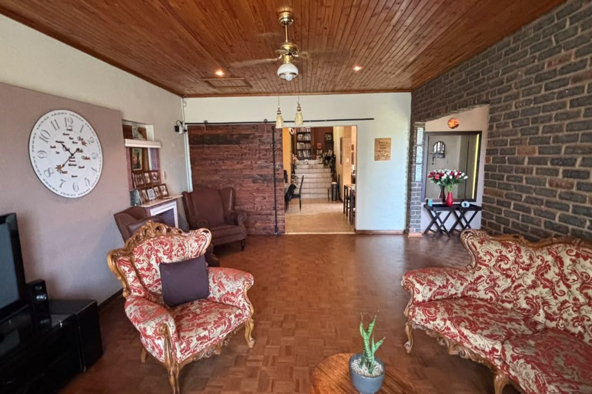 Spacious living room featuring a warm timber ceiling, exposed brick wall, parquet flooring, and a rustic sliding barn door leading to adjacent areas.