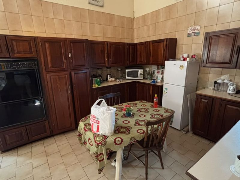 A functional kitchen featuring traditional dark wood cabinetry, tiled backsplash, and tiled flooring, offering a classic layout with ample storage space.