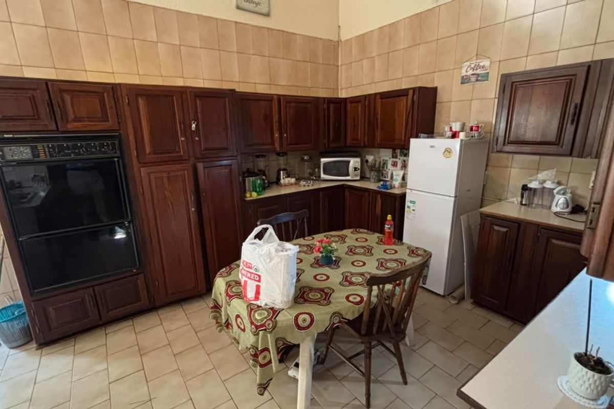 A functional kitchen featuring traditional dark wood cabinetry, tiled backsplash, and tiled flooring, offering a classic layout with ample storage space.