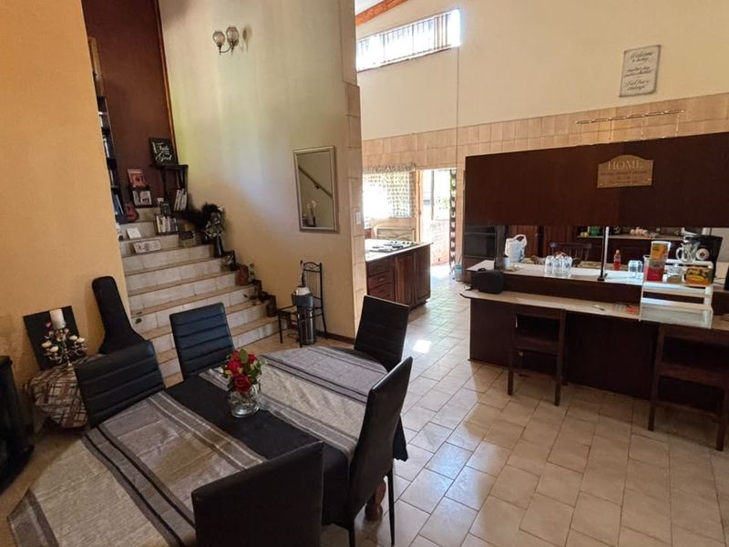 Open plan living and dining area featuring a breakfast bar, tiled flooring, and a staircase leading to the upper level.