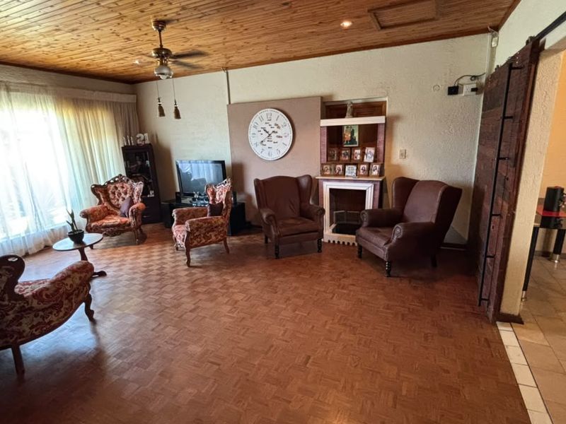 Spacious living room featuring warm timber ceilings, classic parquet flooring, and a built-in fireplace, offering a cozy and traditional atmosphere.