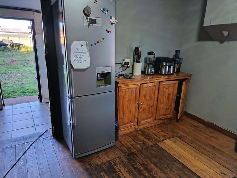 A kitchen area featuring timber cabinetry and wooden flooring, with direct access to an outdoor space.