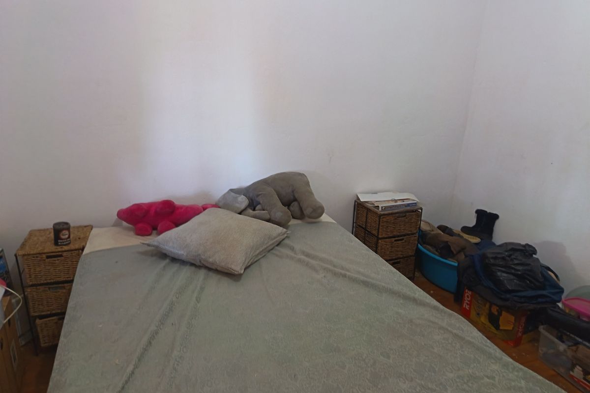 A bedroom featuring hardwood flooring and plain white walls, offering a blank canvas for potential interior design updates.