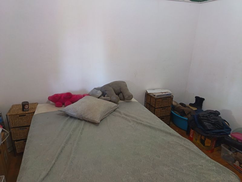 A bedroom featuring hardwood flooring and plain white walls, offering a blank canvas for potential interior design updates.